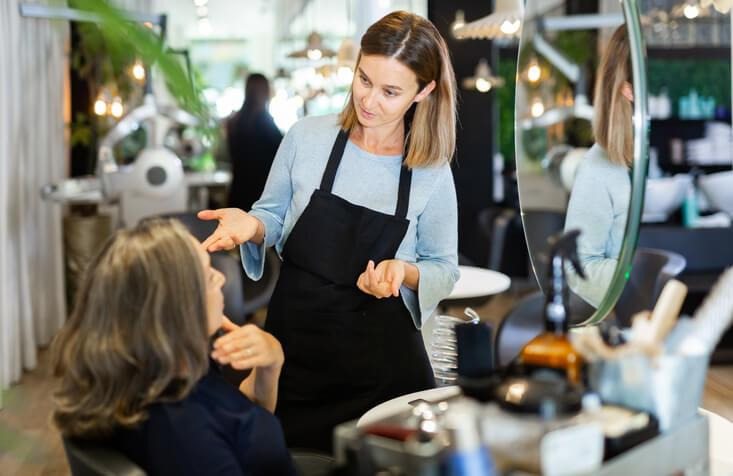 A licensed cosmetologist working with a client in a salon