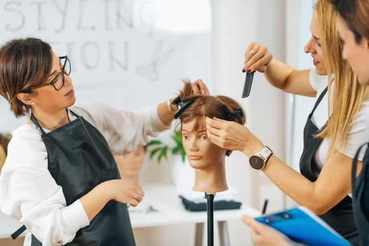 A cosmetology student practicing hairstyling techniques during beauty training