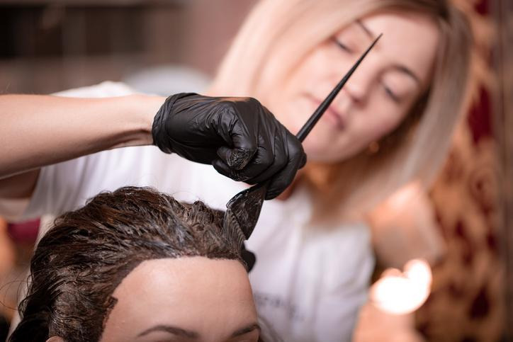 Licensed cosmetologist providing a hair coloring service to a client